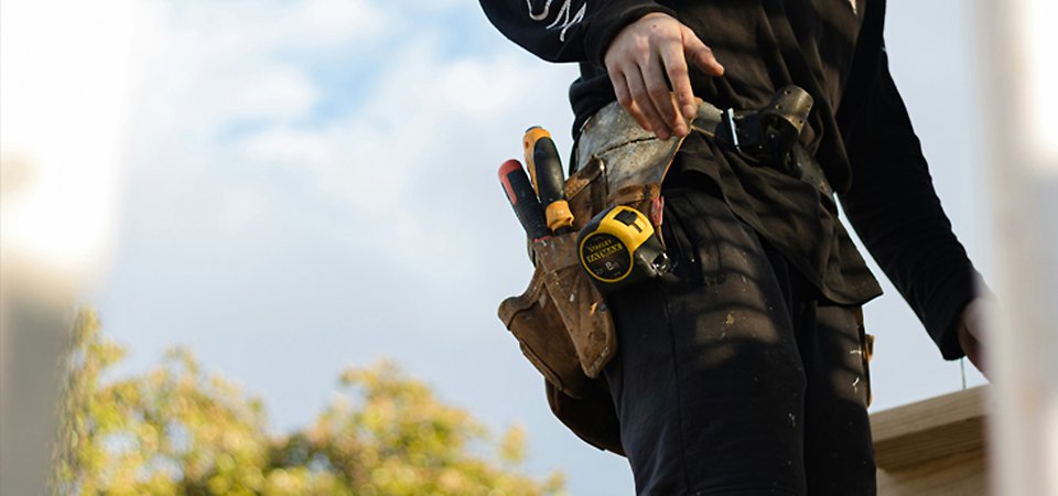 Manlig student blir instruerad av lärare vid ett verktyg.